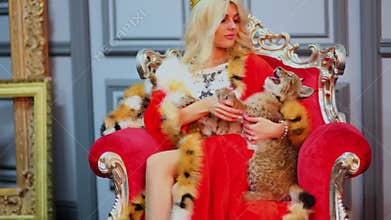 Blonde in red cloak sits in chair and plays with