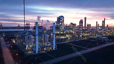 Chimneys of big oil refinery at sunrise polluting environment. Night