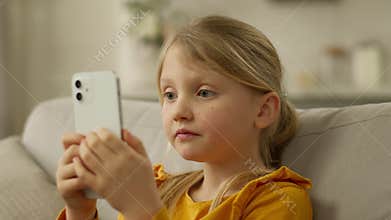 Little European girl holding mobile phone smartphone cellphone surprised wow shocked unexpected emotional amaze victory