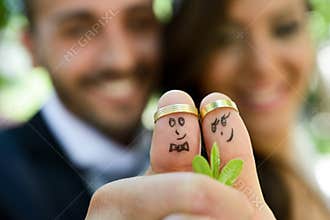 Wedding rings on their fingers painted with the bride and groom