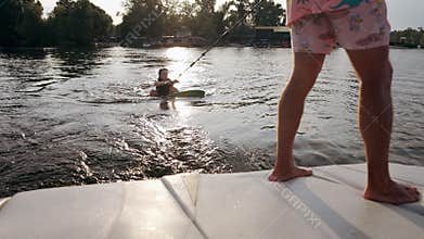 The girl is in the water trying to get on the wakeboard.