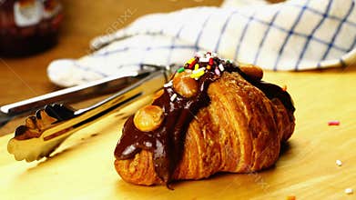 Sprinkling rainbow sprinkles over croissant garnished with chocolate.