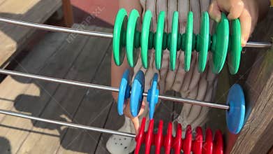 A little child calculates math on a colored abacus, while playing on the playground.