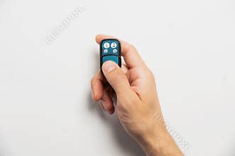 Remote control for door or garage or gate in male hand on white background. Modern technologies and home protection