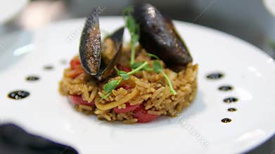 Large mussels rice with seafood cooking traditional Spanish paella on a stove. Chef cooking food on fire from mussels