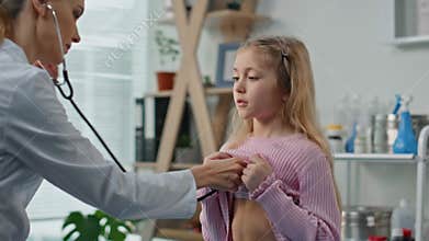 Closeup doctor listening girl lungs in examination room. Cute kid check health