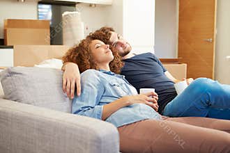 Couple Relaxing On Sofa With Hot Drink In New Home