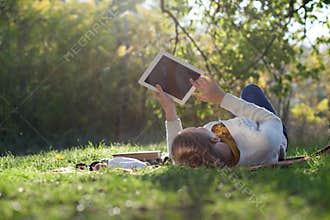 Woman lying on bedding on green grass with ipad
