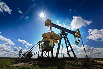Operating oil and gas well profiled on sunny sky