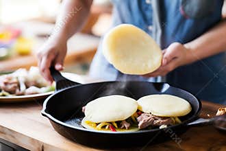 arepas in a cast iron pan with a slice being taken