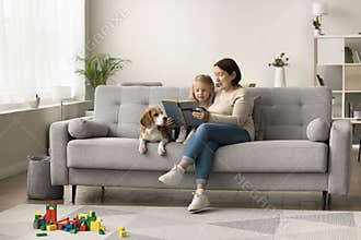 Loving dog owner grandma teaching little granddaughter to read book