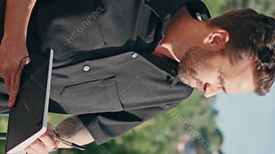 Pensive author writing notebook at cityscape vertical close up. Man making notes