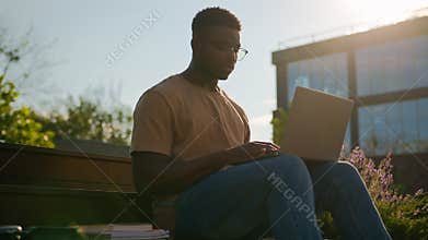 African American man student guy studying outdoors with computer male study in city near university college campus