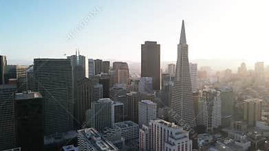 Aerial view of a city skyline bathed in soft sunlight with modern skyscrapers and clear blue sky