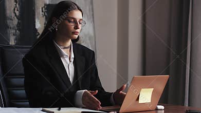 Confident and cheerful caucasian brunette woman opening and typing on a laptop. Young female professional writing an