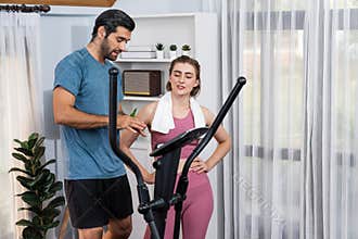 Athletic and sporty couple running on elliptical running machine at gaiety home.