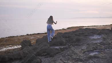 Beautiful girl walking on rocky beach towards the sea, Spain, Alicante