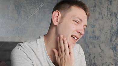Man suffering from strong toothache. Upset male with caries, pulpitis, tooth abscess, teeth sensitivity sitting at home