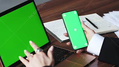Close up woman using smartphone green screen with laptop computer Chromakey. Close up shot of woman&#x27;s hands holding