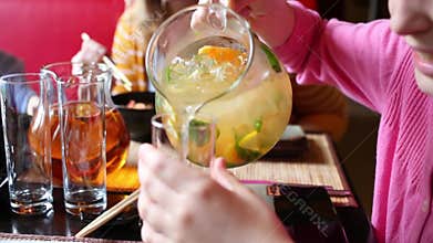 Girl in pink pouring lemonade from carafe into