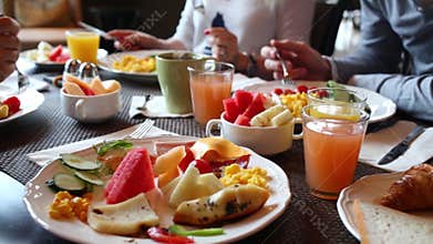 Table with food and glasses of juice, hands of