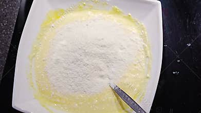 A woman&#x27;s hand mixes the dough with the added flour with a spoon.