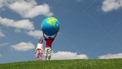 boy with inflatable ball and small girl on meadow