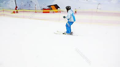Little boy slides on alpine skis from snowy slope,