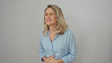 Painfully sick young blonde woman suffering stomachache, hand on aching belly. standing, wearing shirt against isolated white