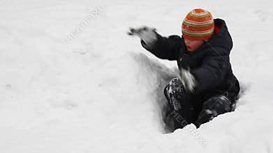boy sits among snow and builds of it wall in