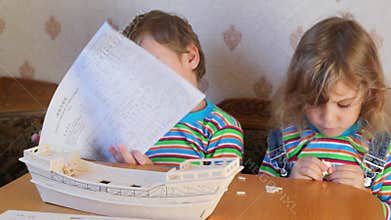 sitting boy and girl constructing toy model of