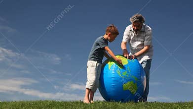 senior with his grandson stand on grass and study
