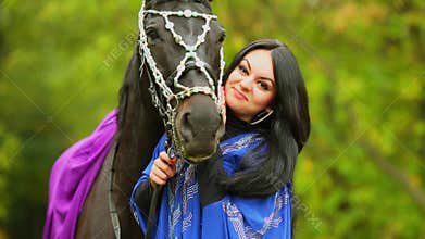Brunette in blue clothes pats chestnut horse at