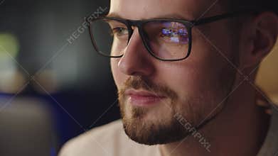 Young guy looking at screen with glasses reflection. Positive student man searching content about war in Ukraine