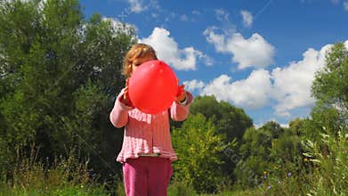 little girl throwing up red balloon in