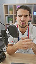 A focused hispanic man with a beard speaks into a microphone in a podcasting studio, suggesting a recording session