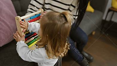 A woman and a young girl engage in learning using an abacus in a cozy living room setting, embodying family, education, and