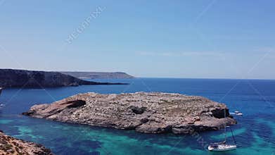 Boats floating in the crystal clear turquoise sea water. Blue lagoon, Comino, Maltese Islands. Aerial static shot