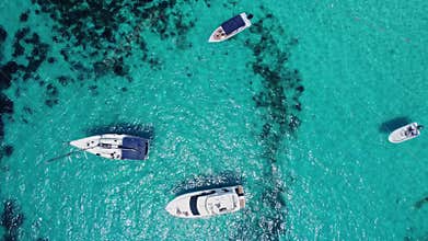 Boats floating in the crystal clear turquoise sea water. Blue lagoon, Comino, Maltese Islands. Aerial high angle view