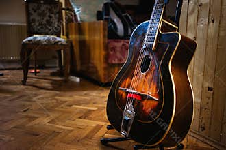 An acoustic gypsy jazz guitar on a stand in the room