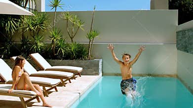 Brother diving into the swimming pool while sister is watching him
