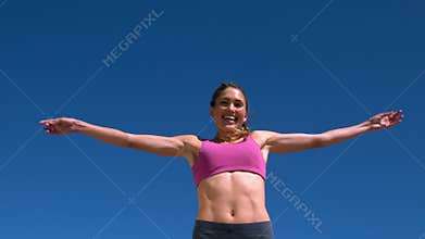Fit blonde smiling and jumping up on sunny day