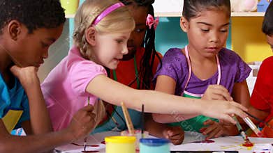 Preschool class painting at table in classroom