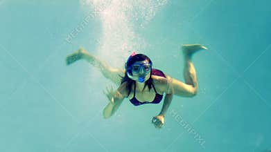 Fit brunette diving into swimming pool wearing snorkel