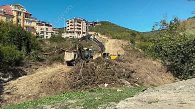 Urban excavator clearing hillside