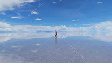 A woman runs across the expansive Salar de Uyuni in Bolivia, her reflection mirrored in the crystal-clear waters beneath a bright
