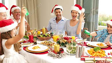 Siblings pulling a christmas cracker at the dinner table