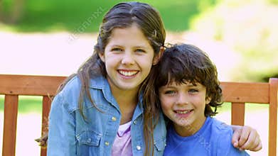 Brother and sister embracing on park bench