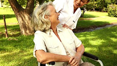 Nurse talking to woman in wheelchair outside