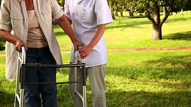 Nurse talking to woman using walker outside